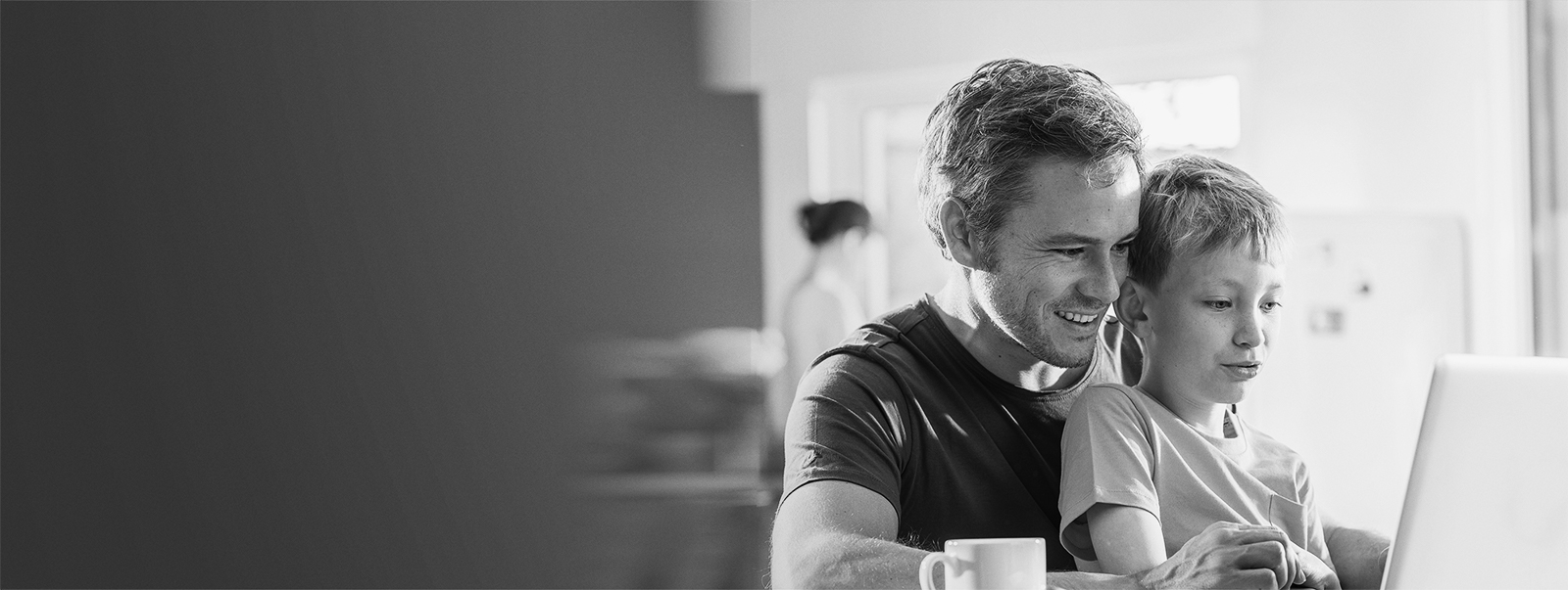 Father with boy on lap looking at laptop